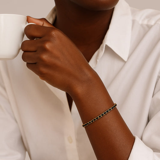 Person holding a white mug with a focus on a bracelet on their wrist.
