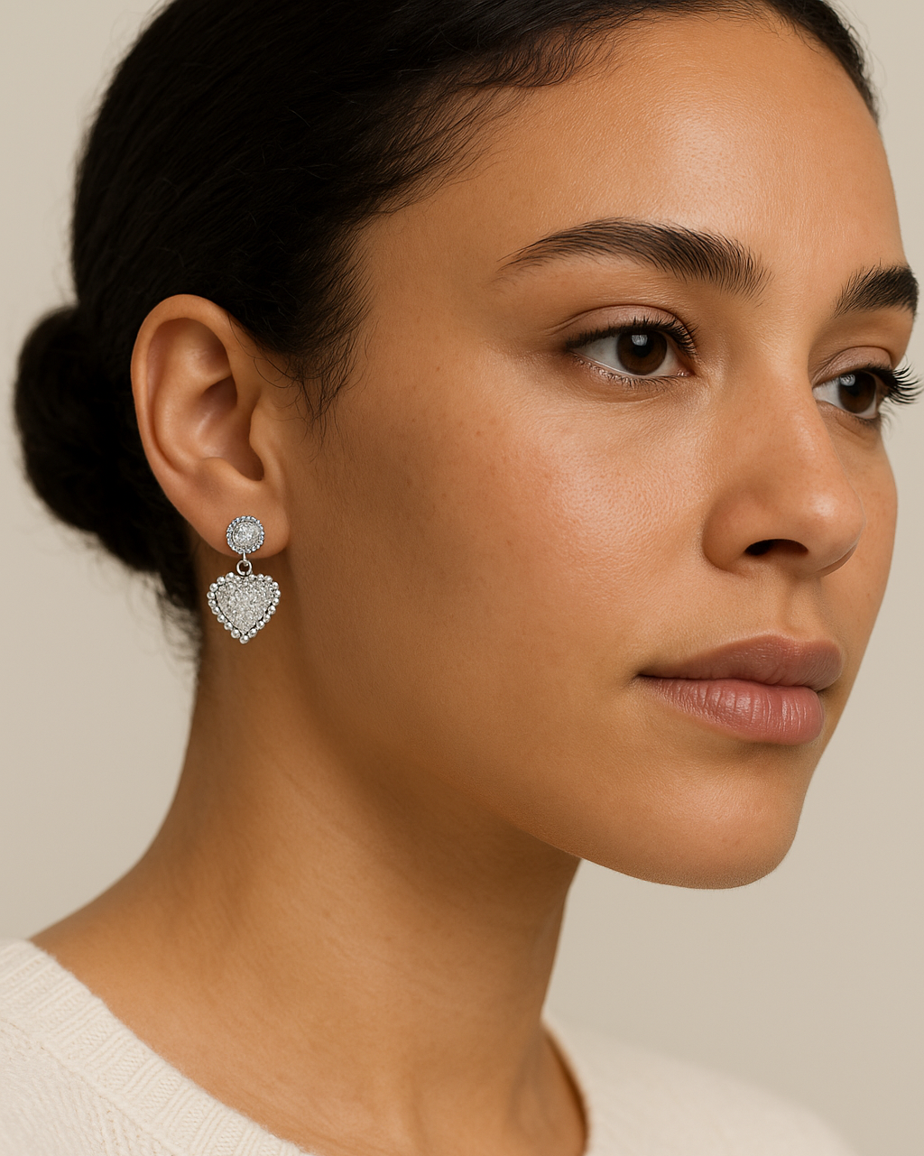 Close-up of a woman wearing heart-shaped earrings with a neutral background