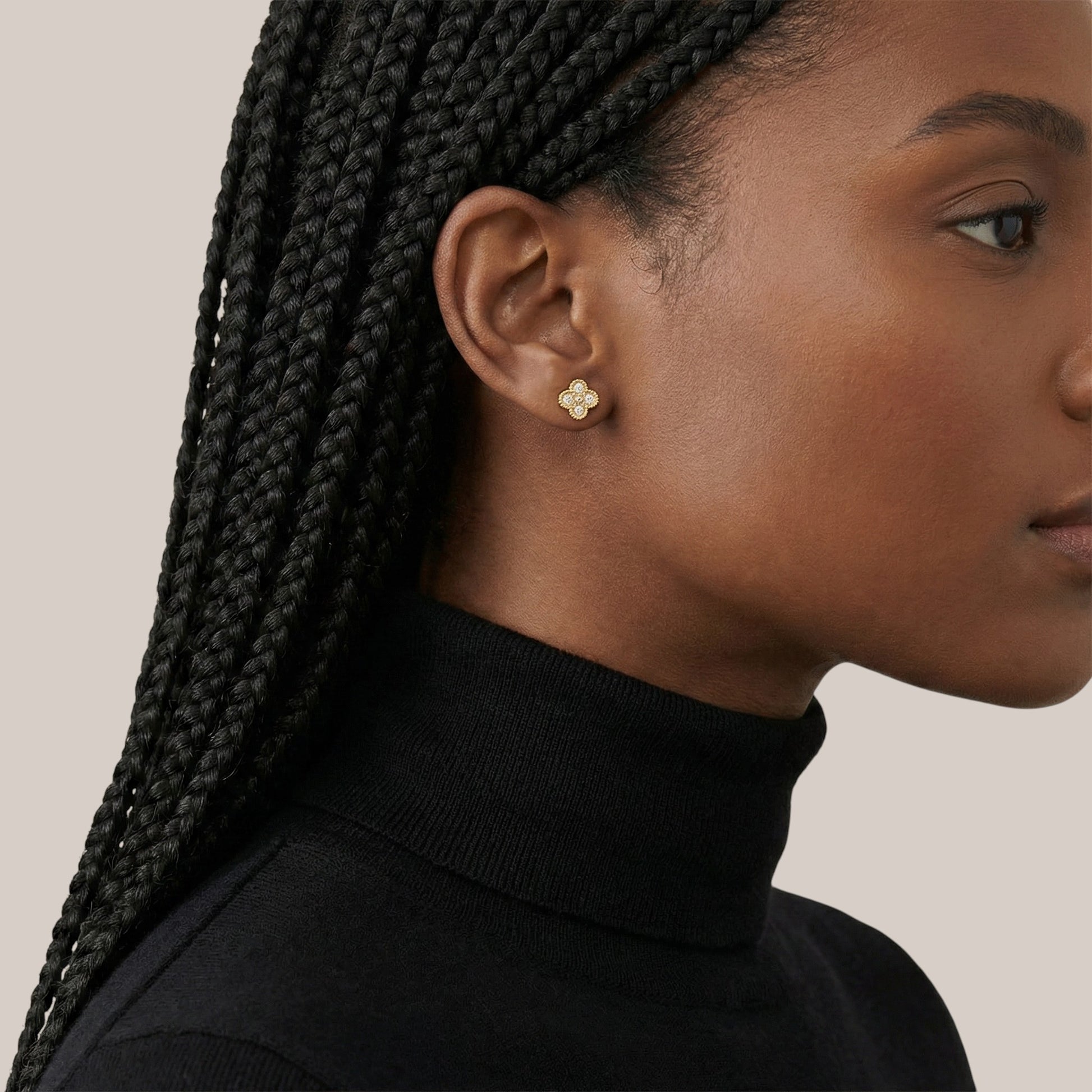 Close-up of a woman wearing a gold earring with a beige background