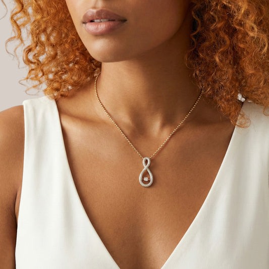 Woman wearing a gold necklace with a silver pendant against a neutral background