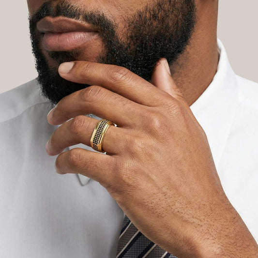 Man wearing a gold ring on his finger, with a neutral background