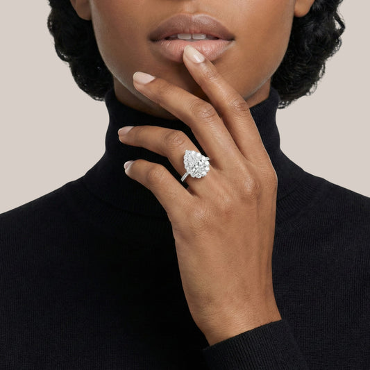 Woman wearing a diamond ring on her finger against a neutral background