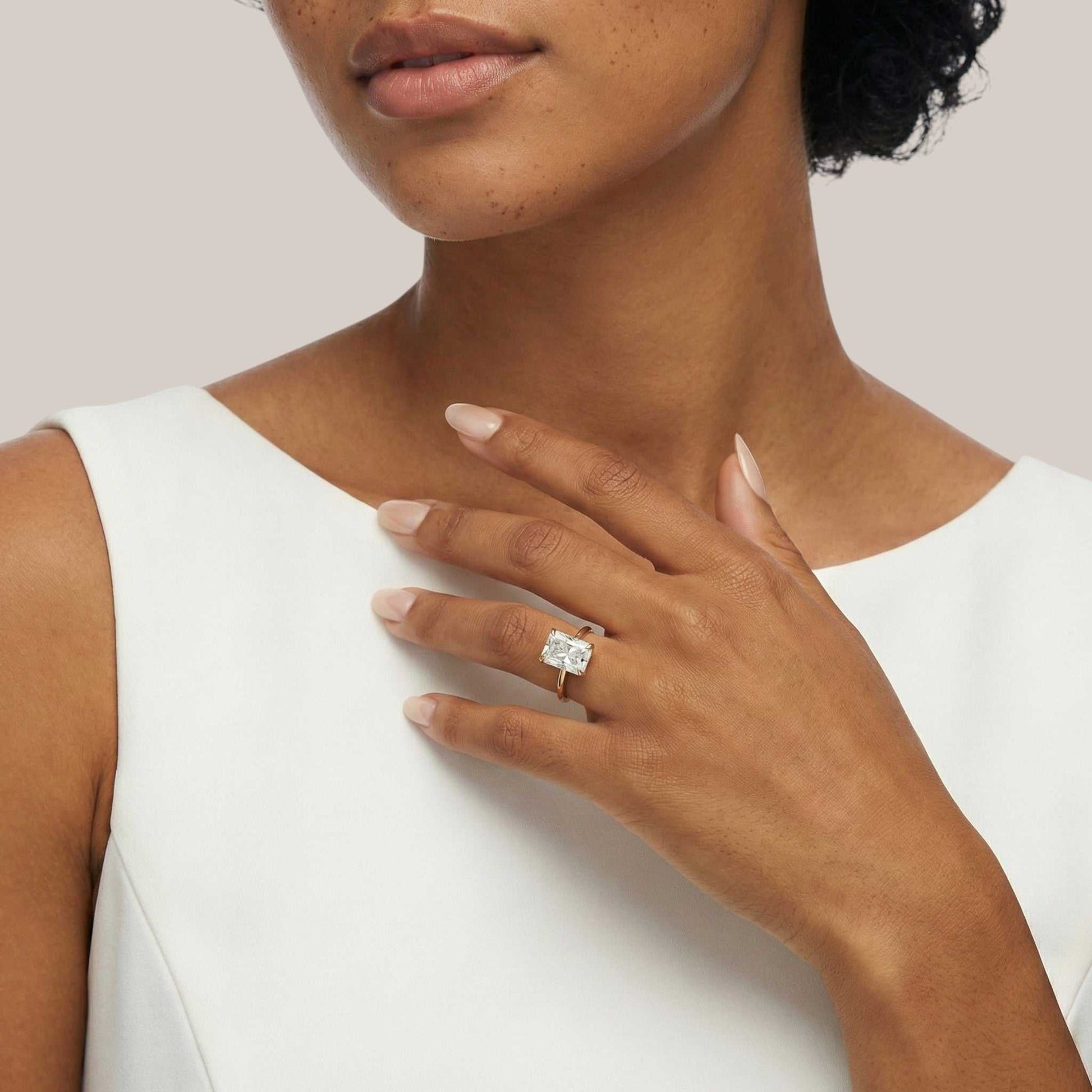 Woman wearing a diamond ring on her hand against a neutral background