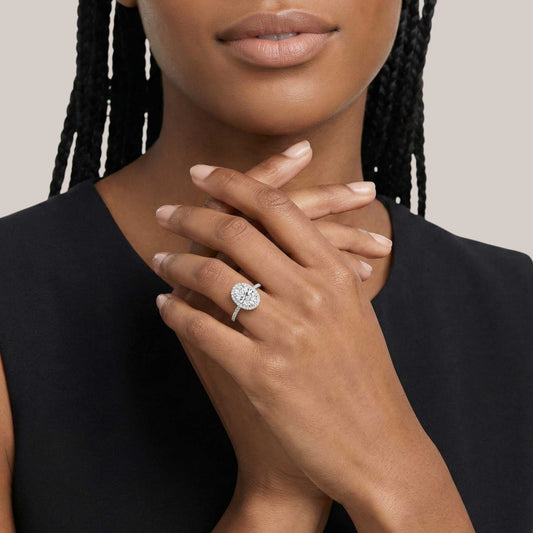 Close-up of a woman's hand wearing a diamond ring on a neutral background