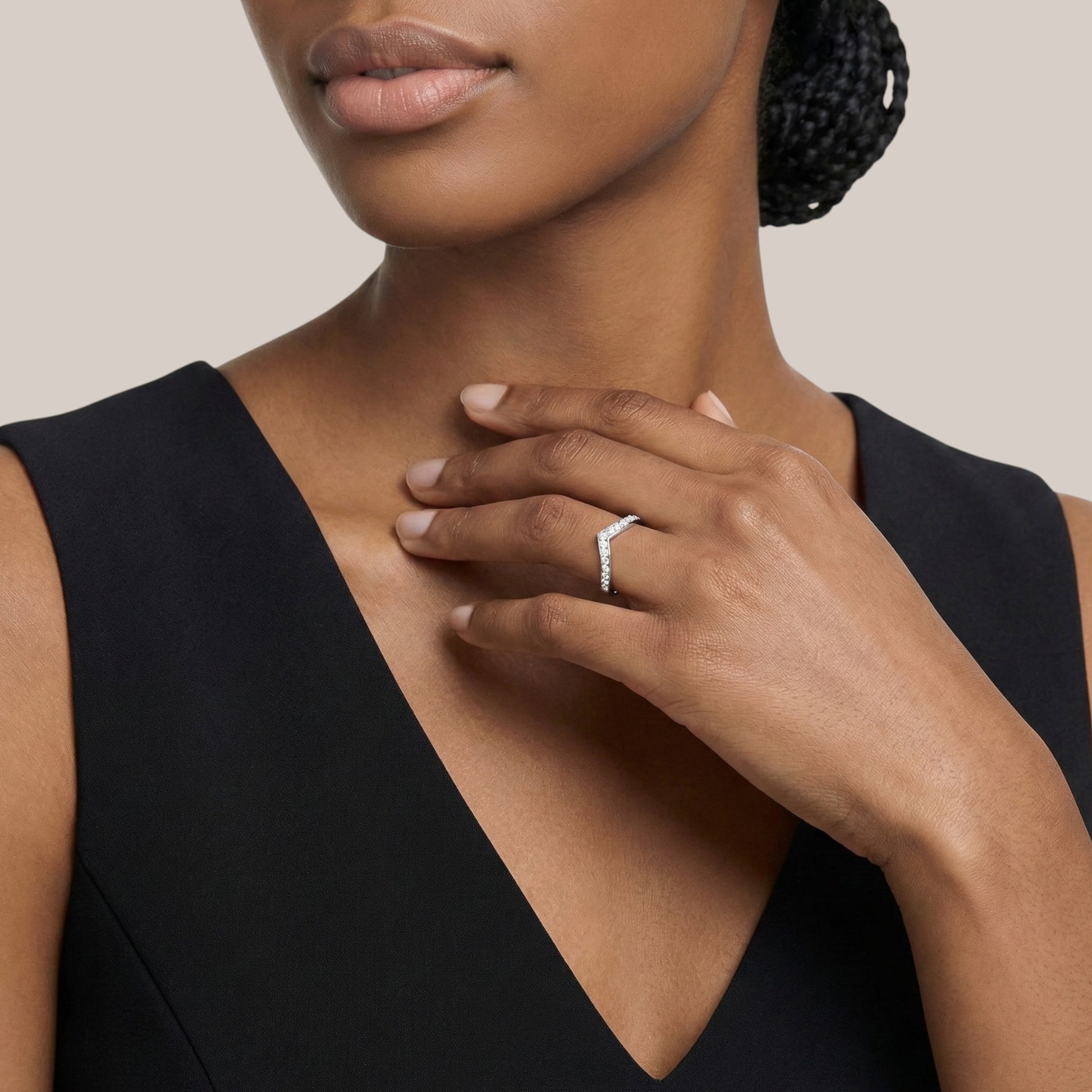 Woman wearing a black dress with a close-up of her hand and ring on a neutral background