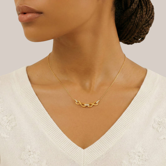 Woman wearing a gold necklace with a plain background