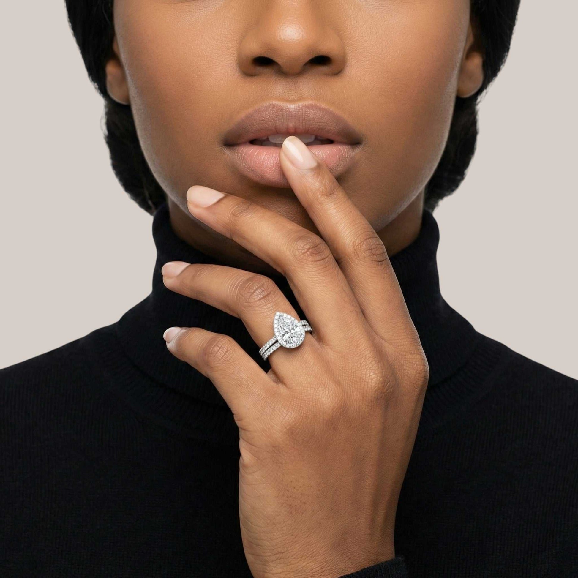 Close-up of a person wearing a diamond ring on a neutral background