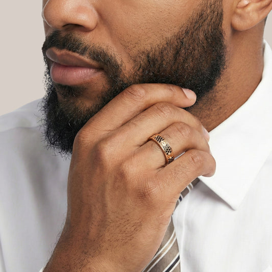 Man wearing a gold ring with a white shirt and striped tie on a light background