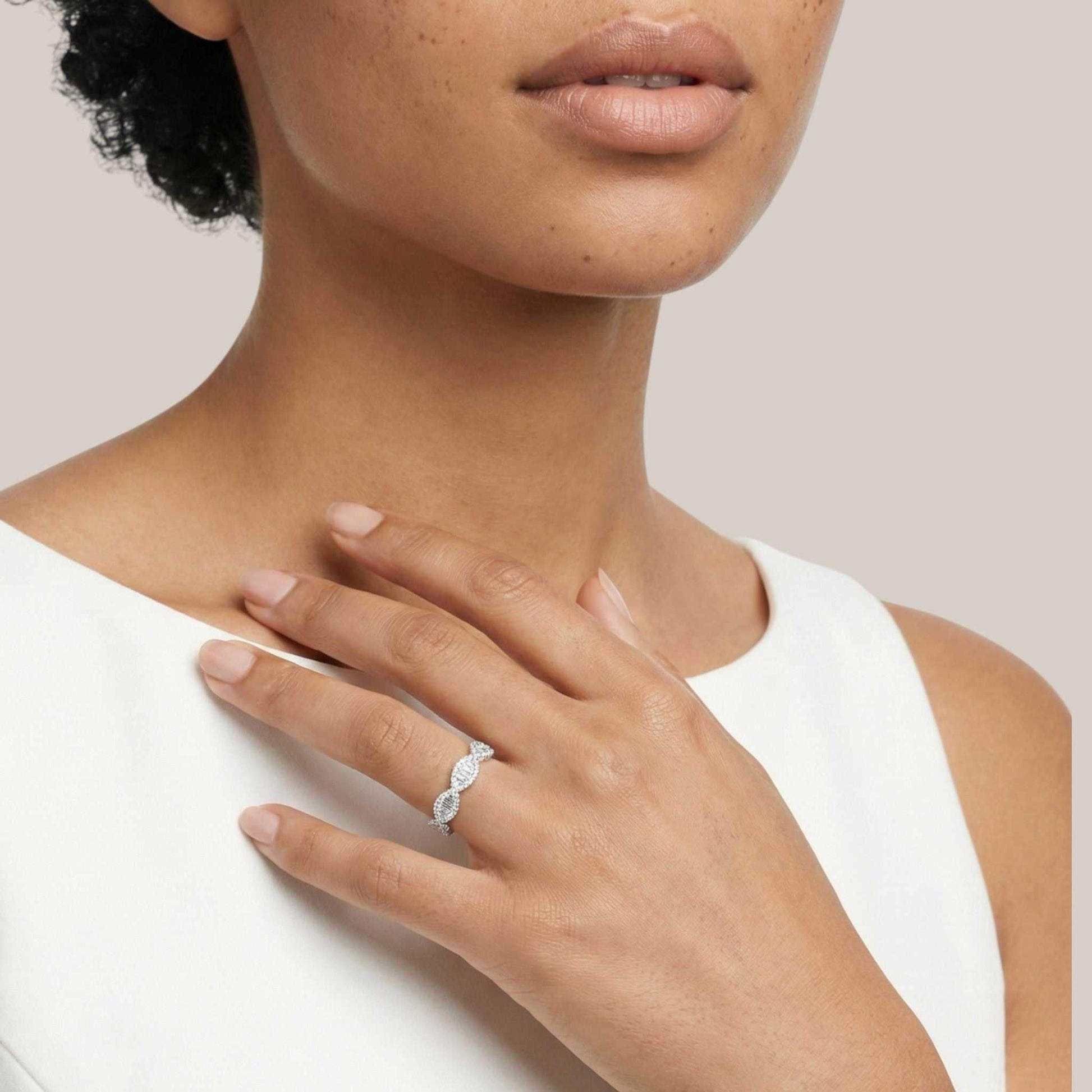 Close-up of a woman's hand wearing a diamond ring on a neutral background