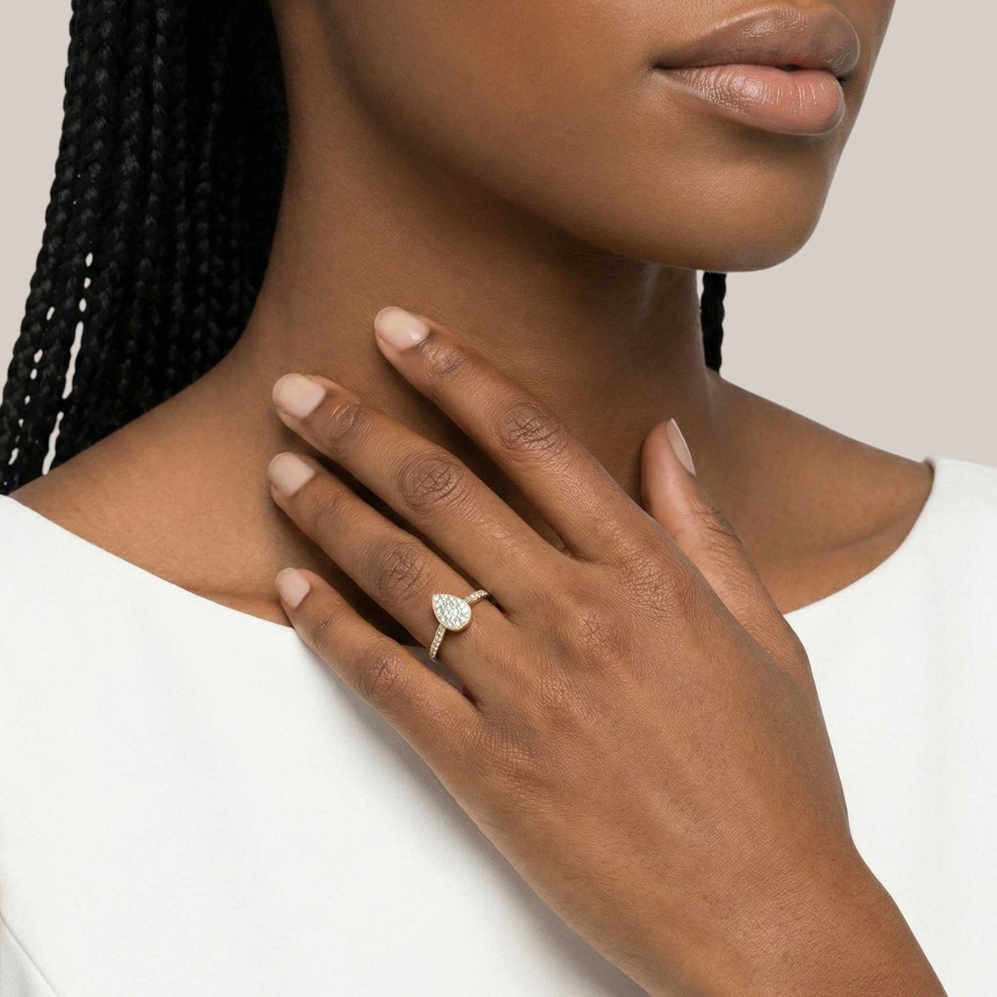 Close-up of a woman's hand wearing a diamond ring on a neutral background
