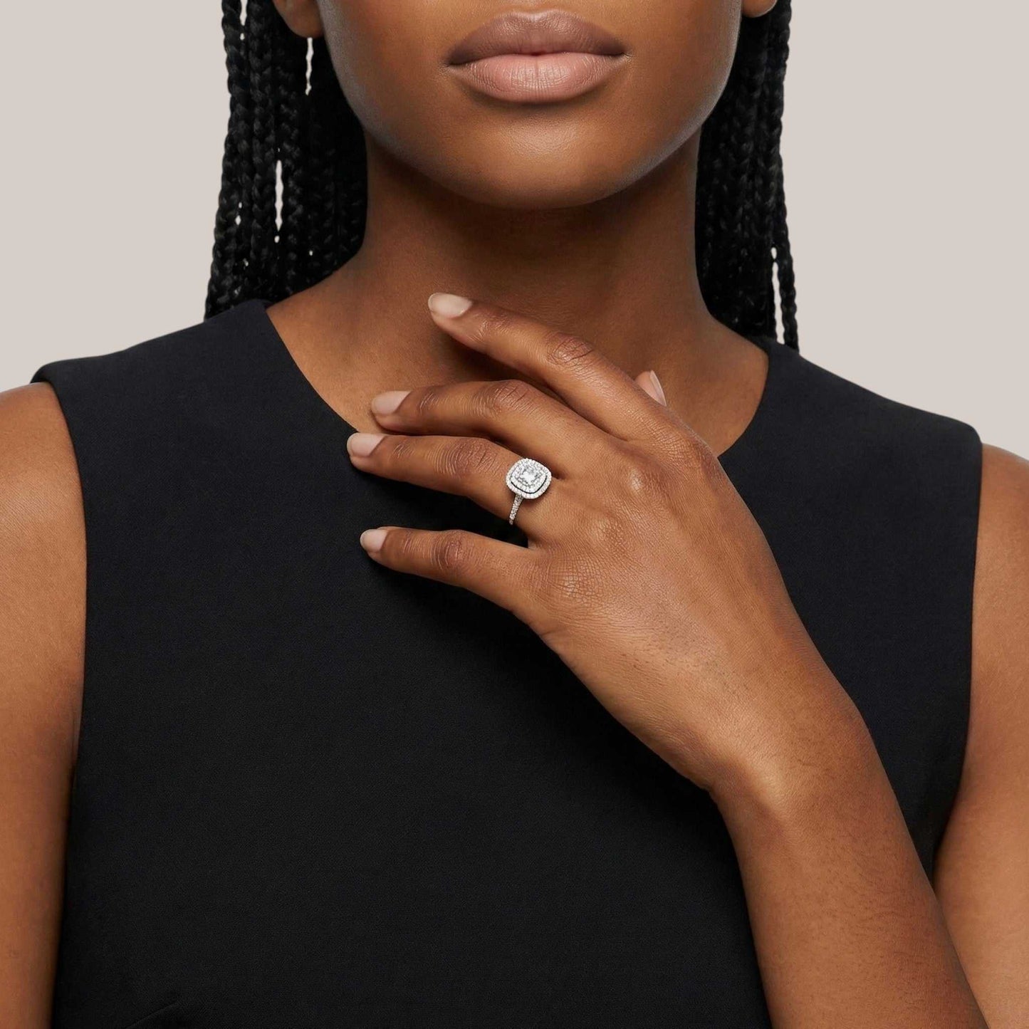 Woman wearing a black sleeveless top with a close-up of her hand and ring.