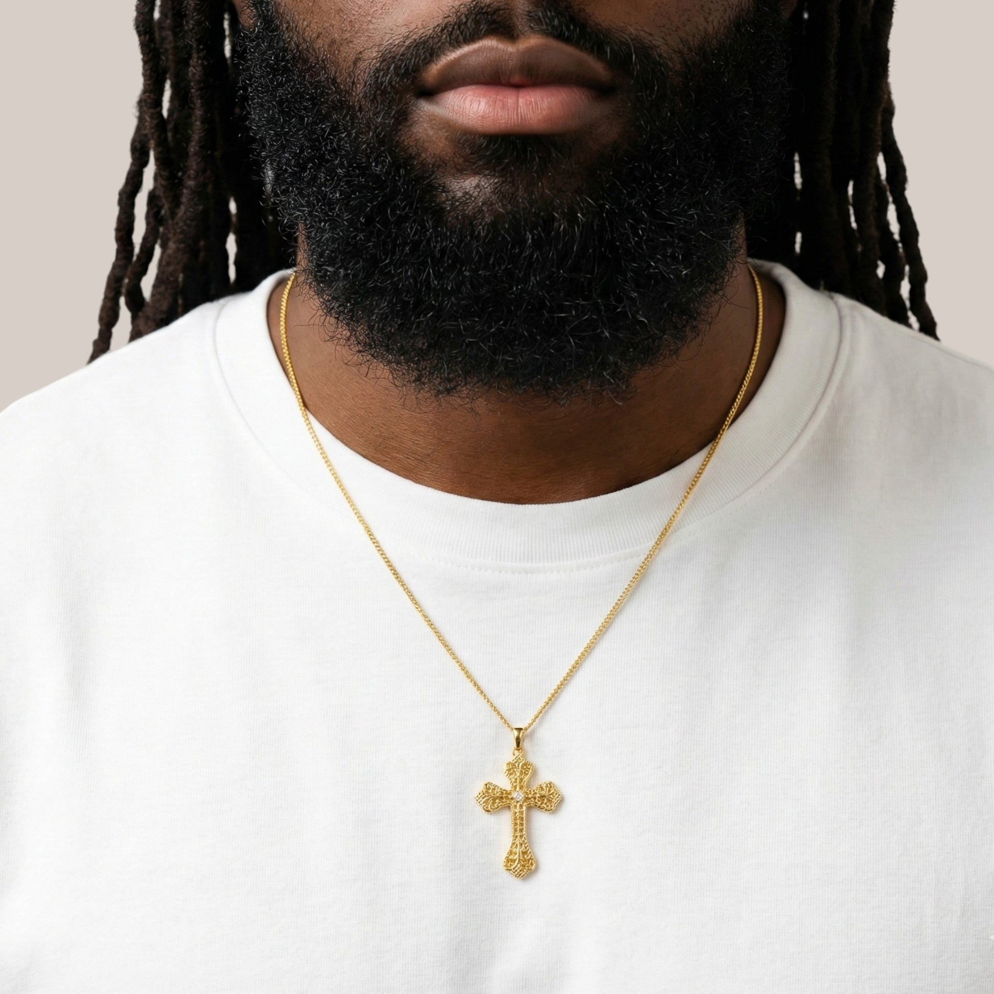 Man wearing a gold cross necklace on a plain background