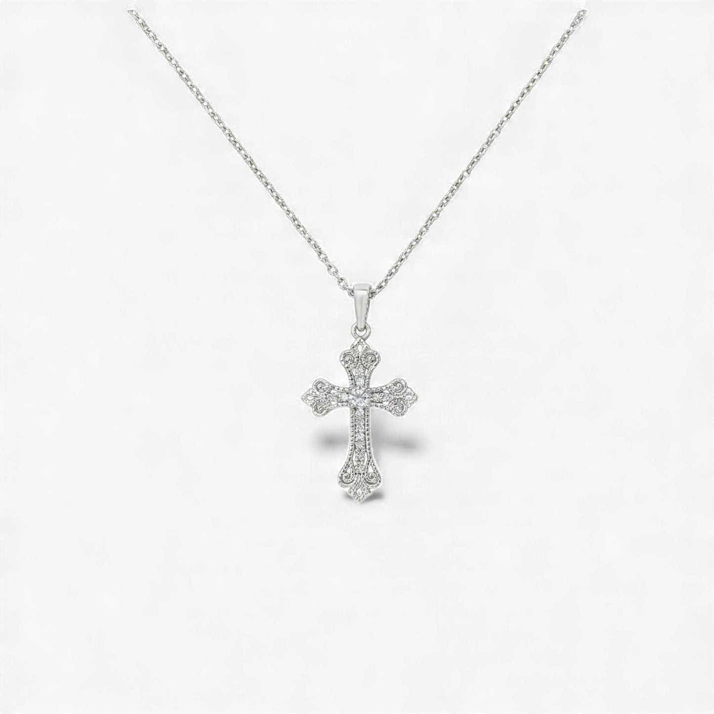 Silver cross pendant necklace on a light gray background