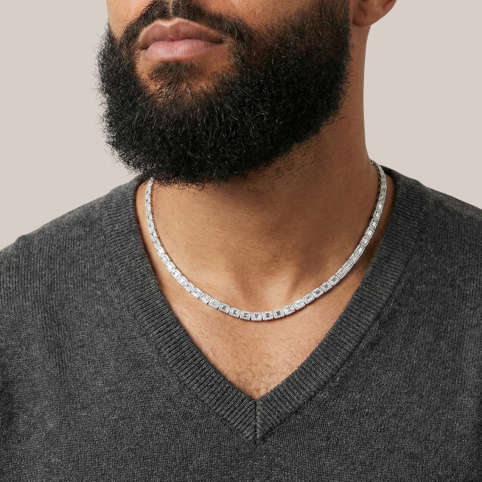 Man wearing a silver chain necklace with a neutral background