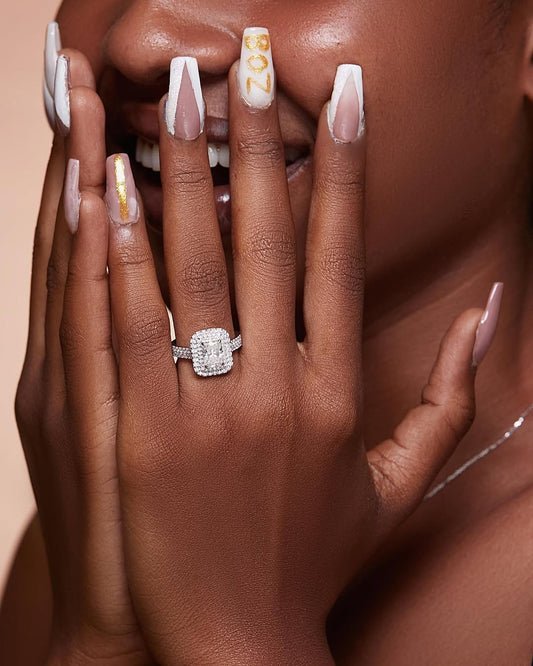 A person showing off their engagement ring and manicured nails, with the ring haloing in the foreground.