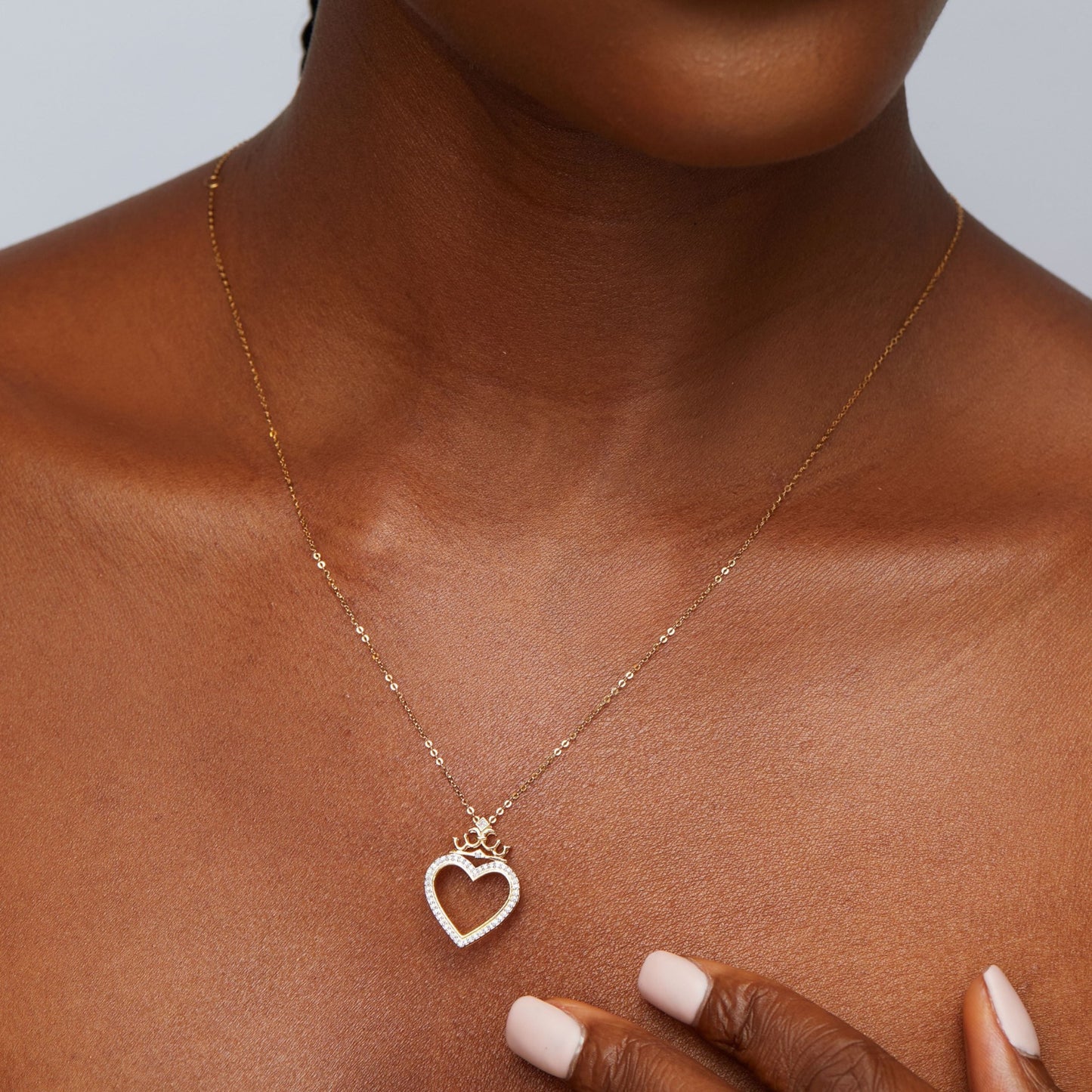 Rose gold heart-shaped necklace on a person's neck with a neutral background