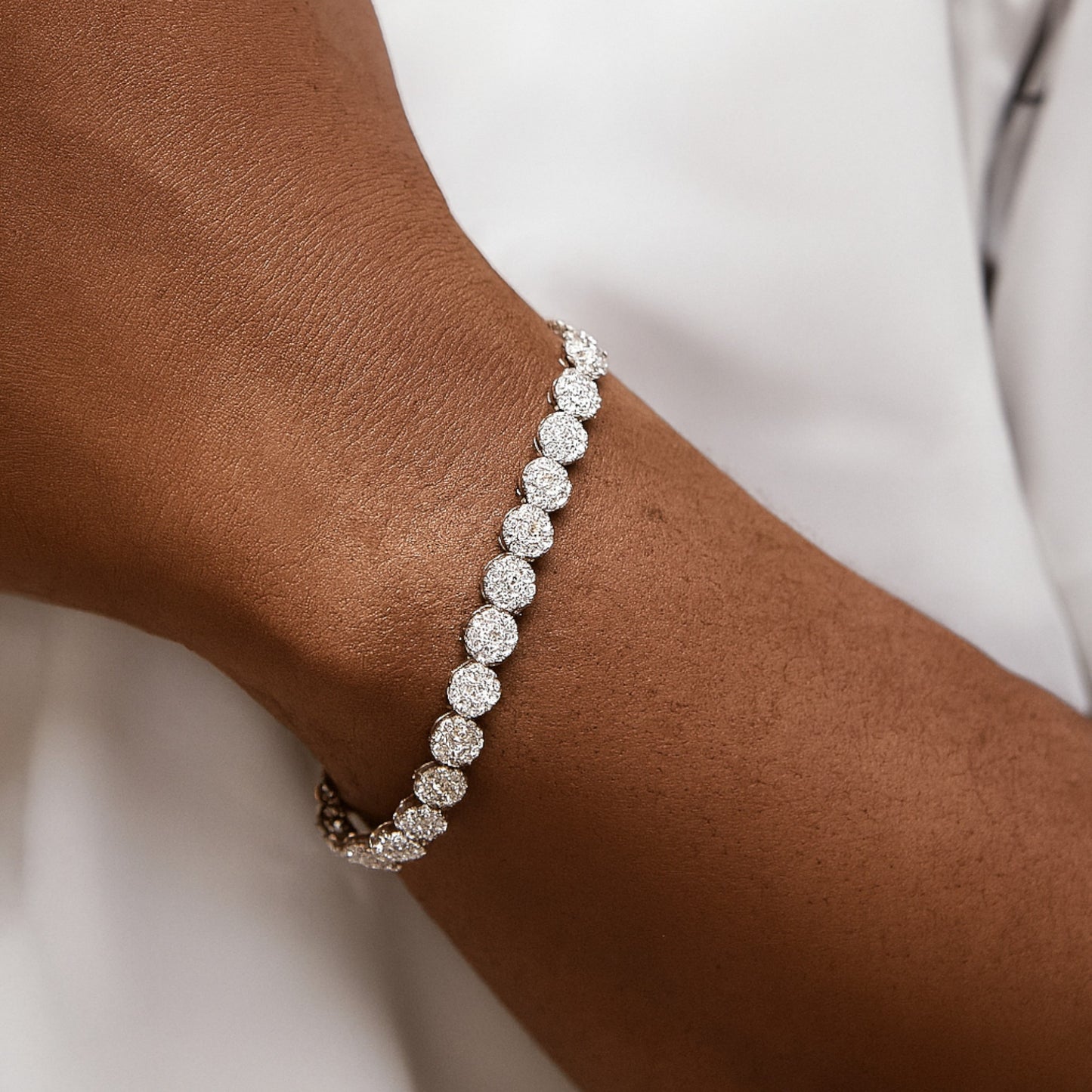 Silver bracelet on a wrist with a plain background