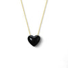 Black heart-shaped pendant on a gold chain against a white background