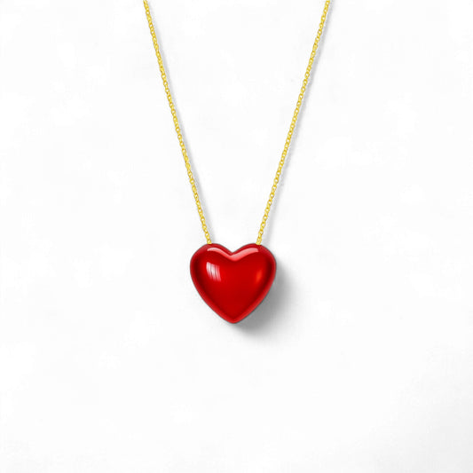 Red heart-shaped pendant on a gold chain against a white background