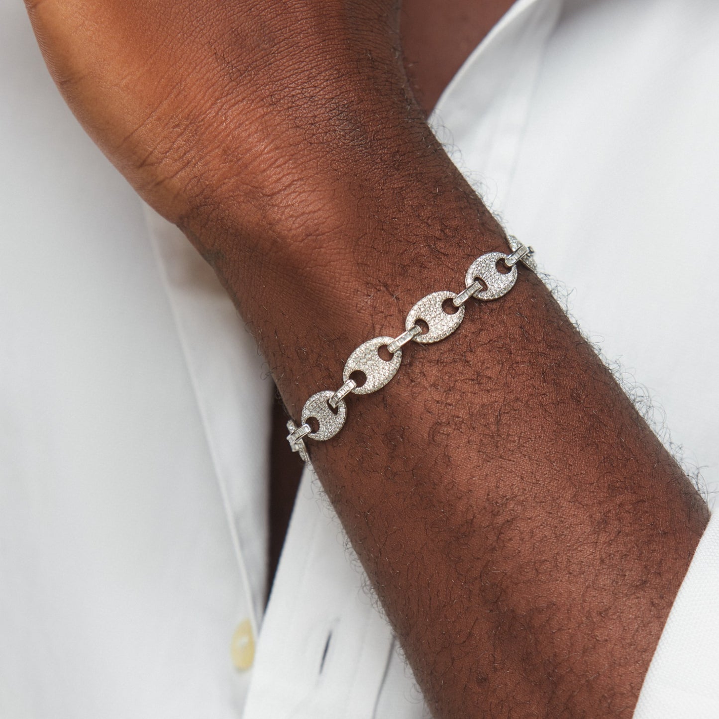 Silver chain bracelet on a wrist with a white shirt background