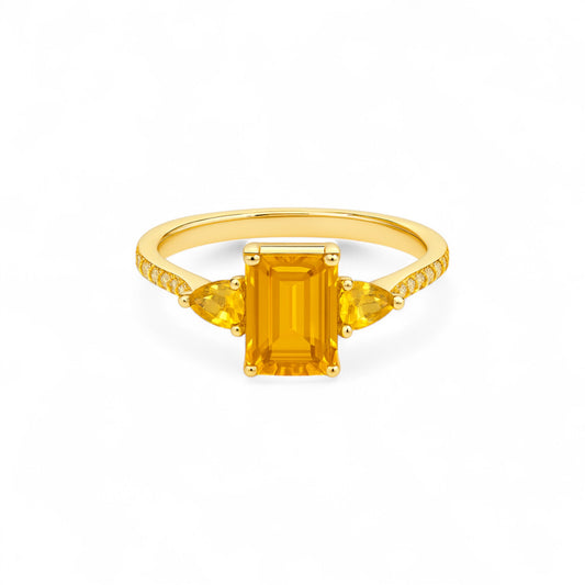 Gold ring with a rectangular yellow gemstone on a white background