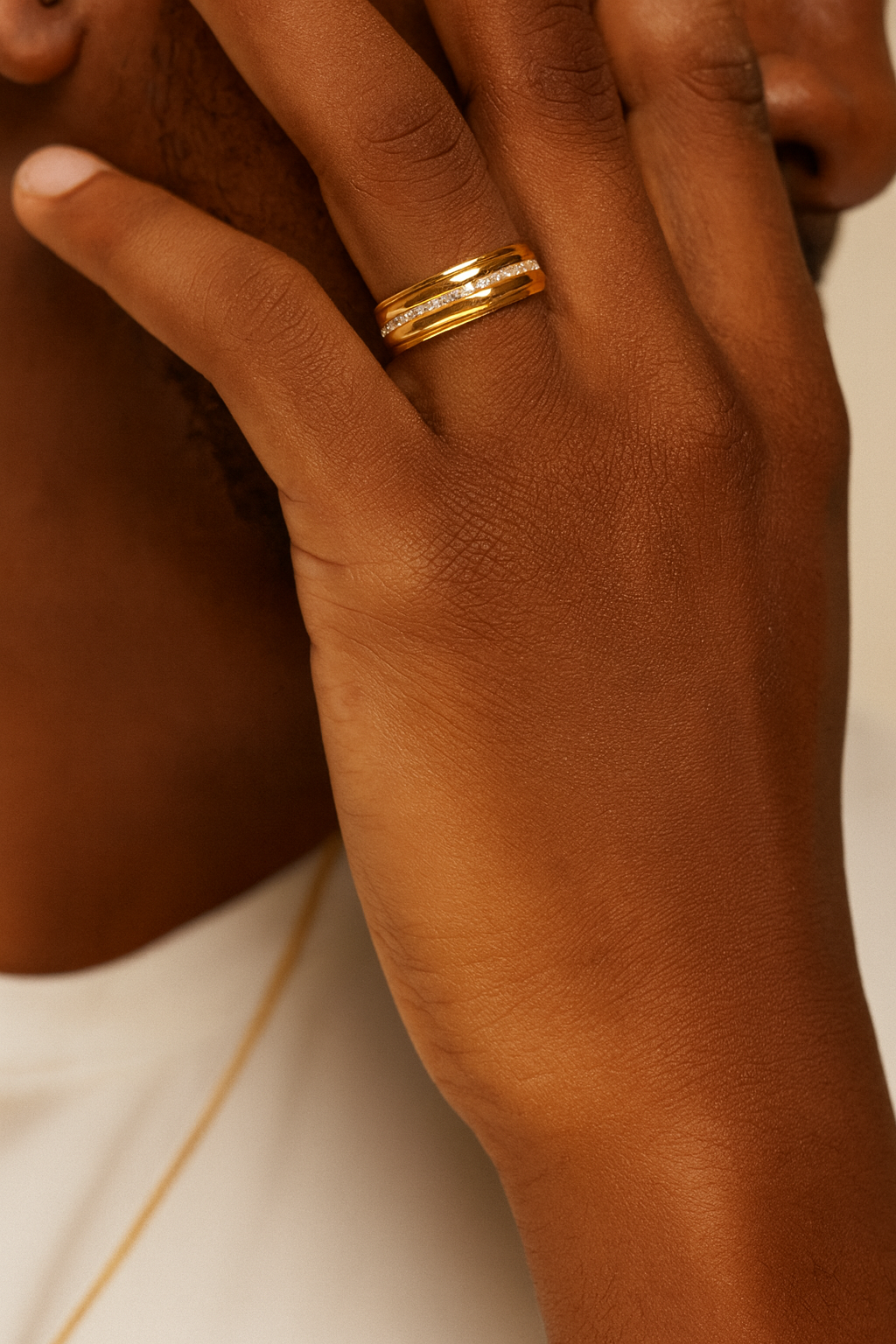 Hand wearing a gold ring with a neutral background