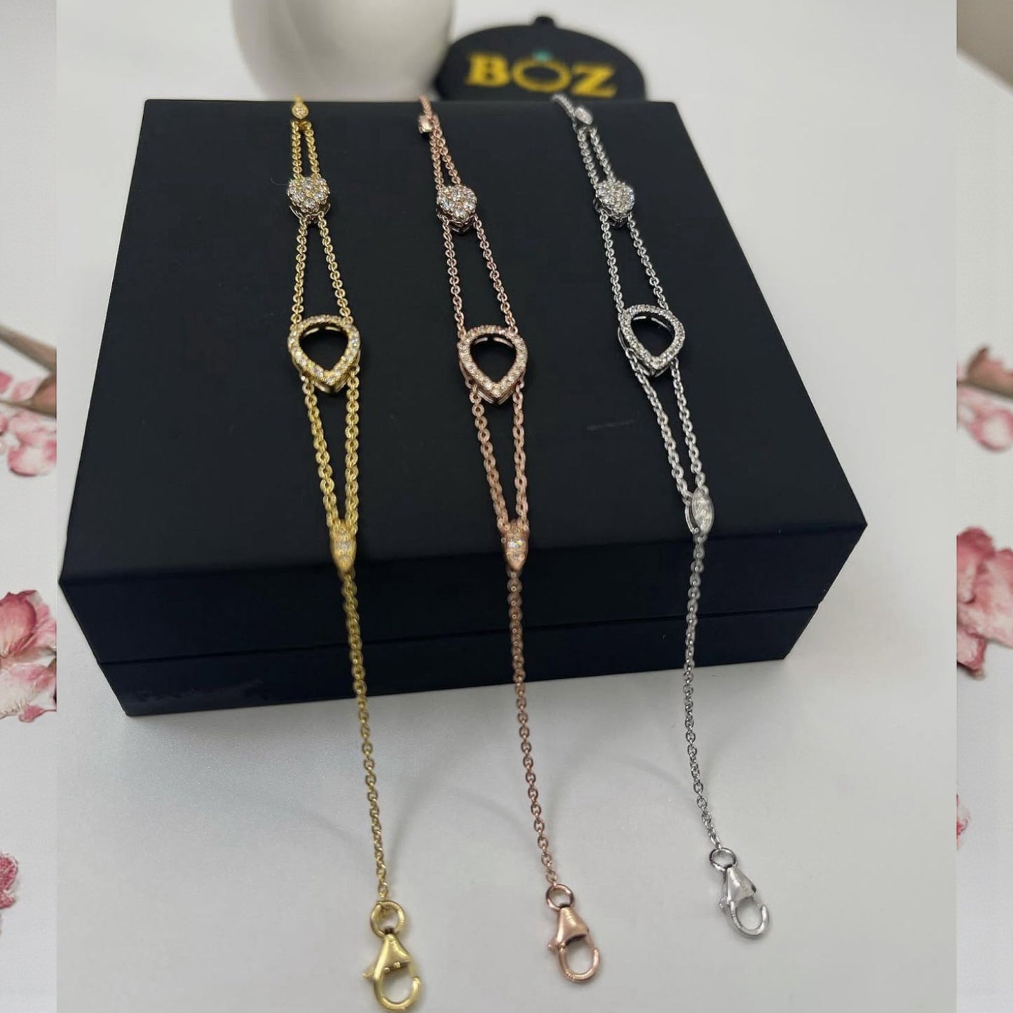 Three necklaces on a black box with 'BOZ' branding in the background.