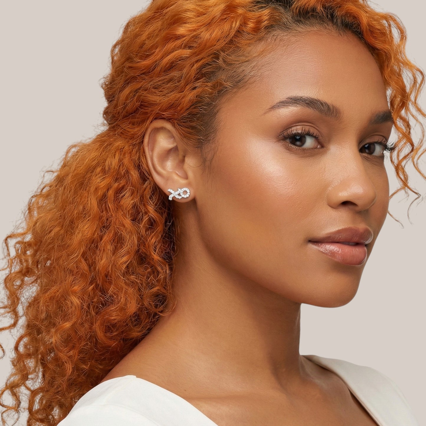 Woman with red hair wearing a white top against a neutral background