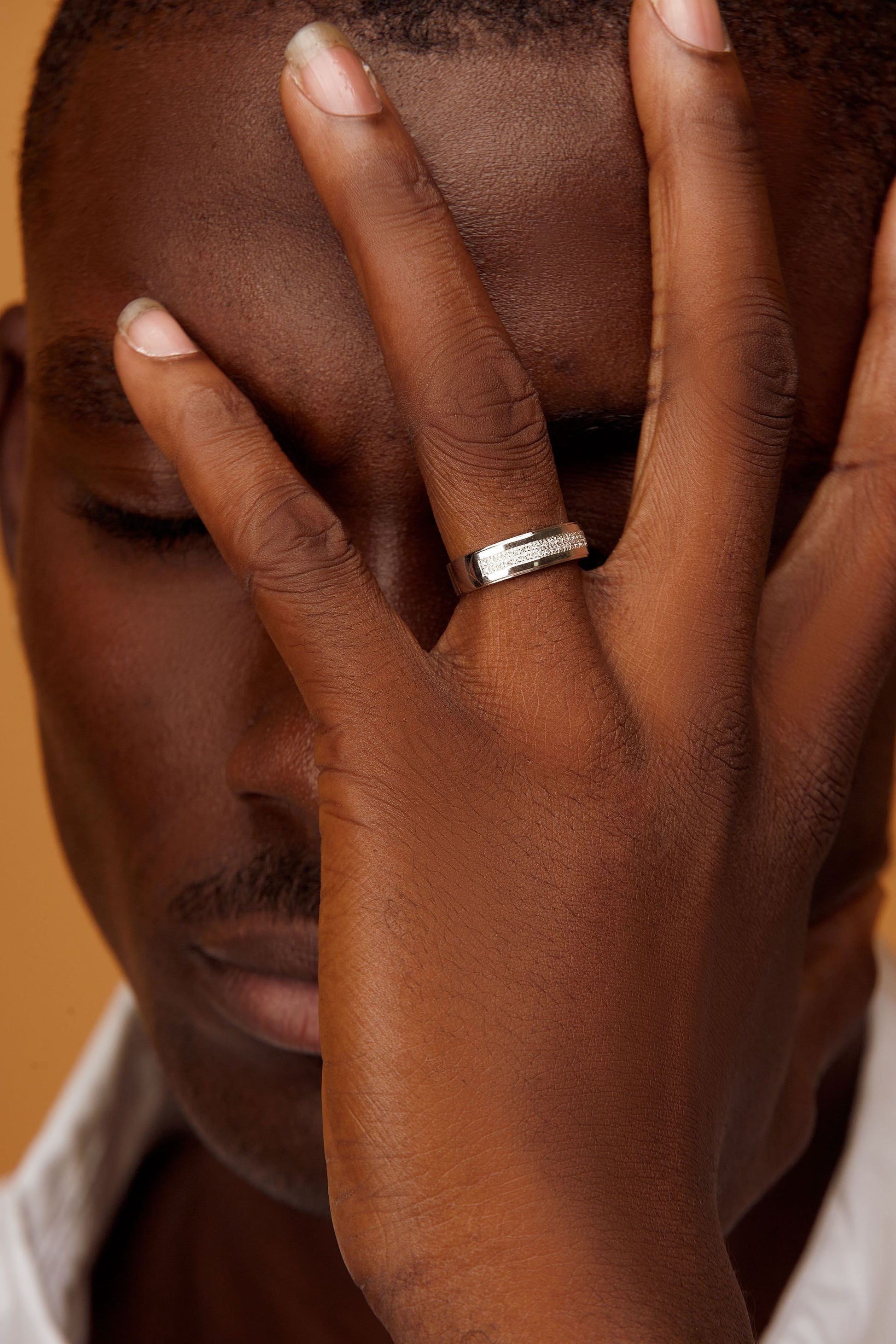 A man's hand displaying a 18K gold ring with a natural diamond on the ring finger.
