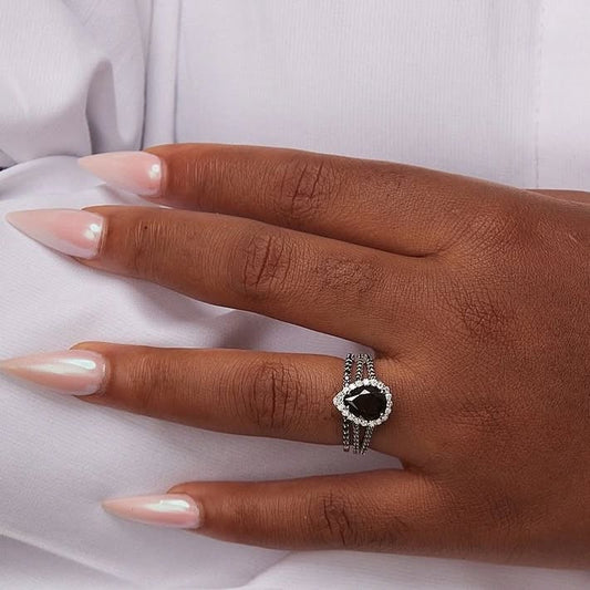 A hand wearing a Black Pear Cut Moissanite ring set in 925 Sterling Silver, showcased on a white background.