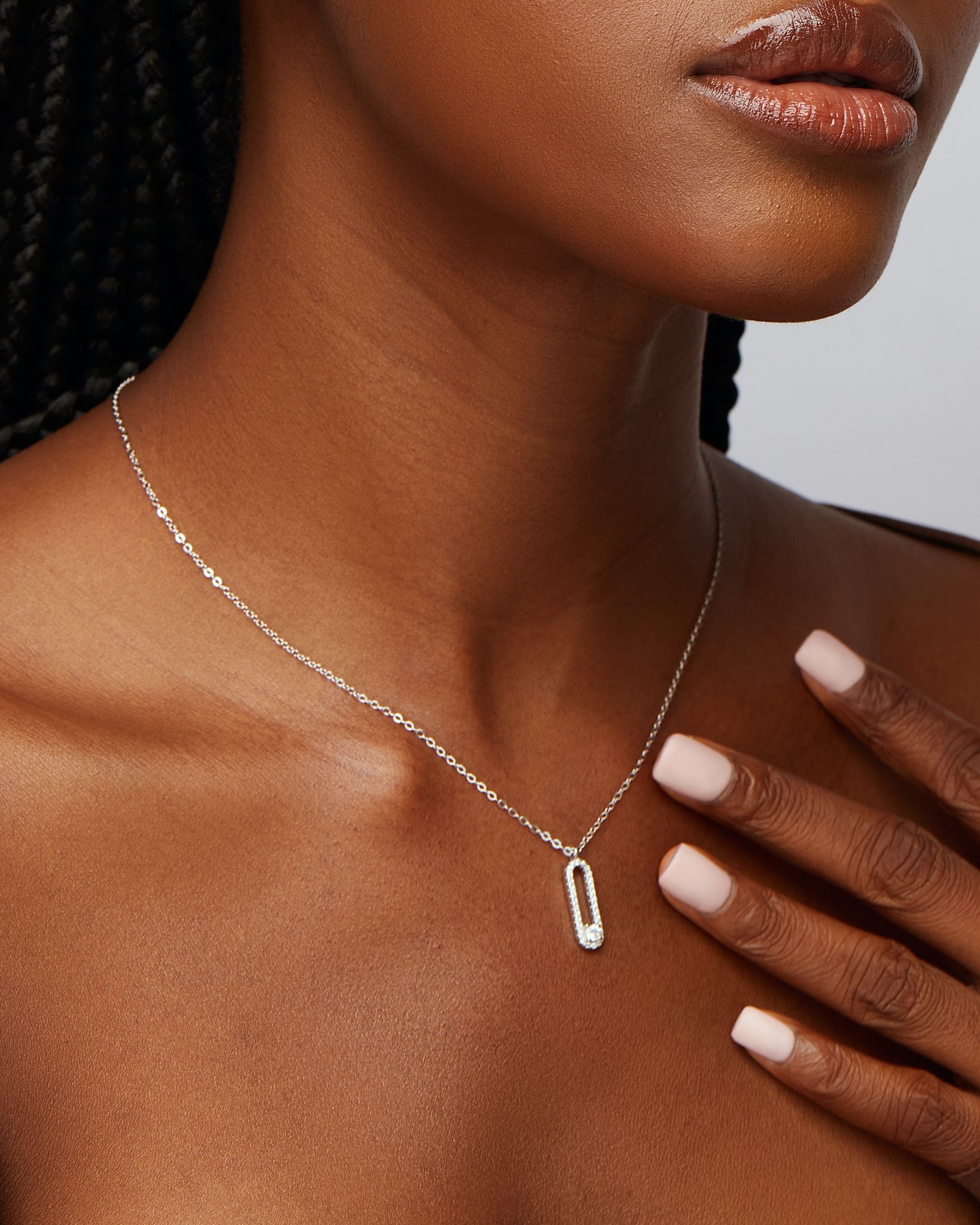 A person wearing a silver necklace with moissanite stones around the collarbone area.