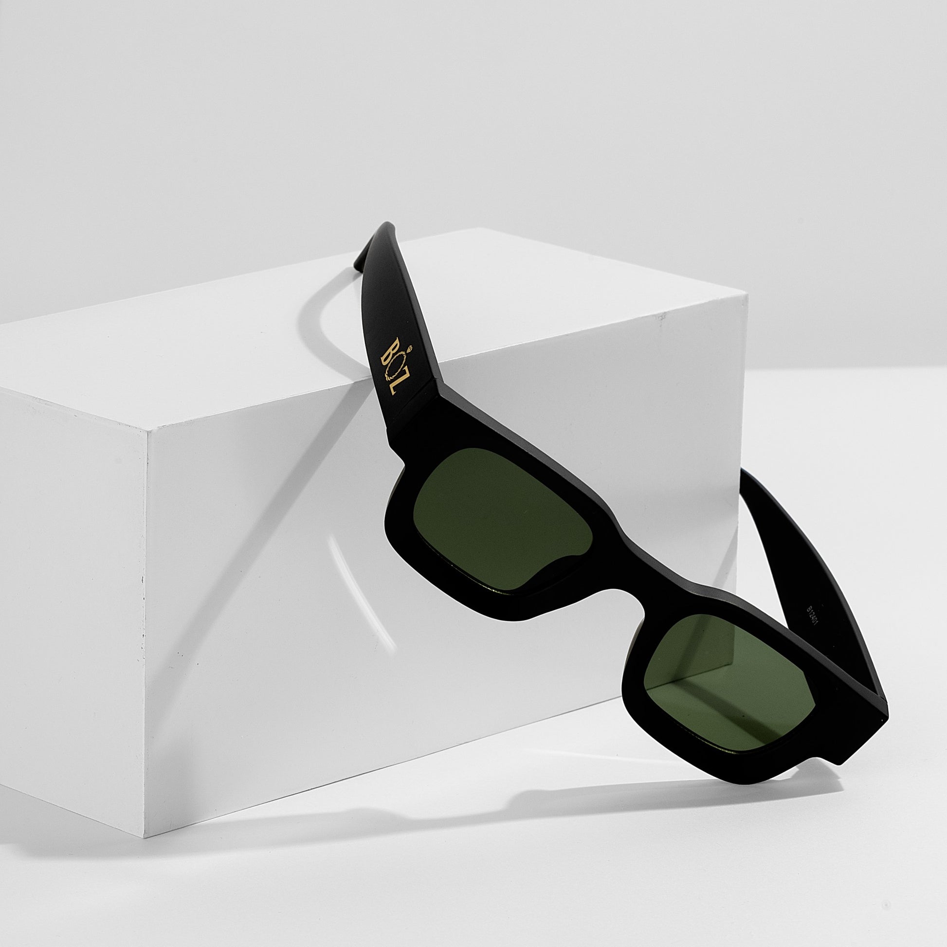 Black sunglasses with green lenses on a white background