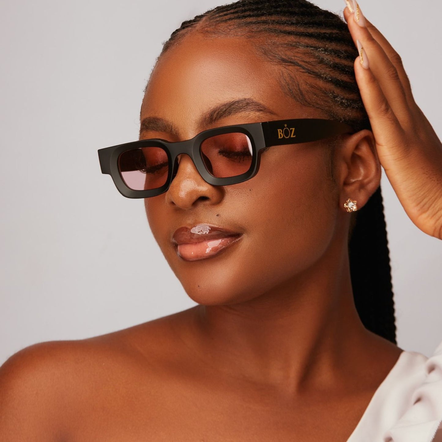 Woman wearing black sunglasses with 'BOZ' brand logo, posing against a neutral background