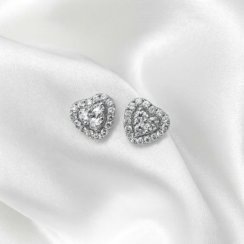 Heart-shaped silver earrings on a white satin background