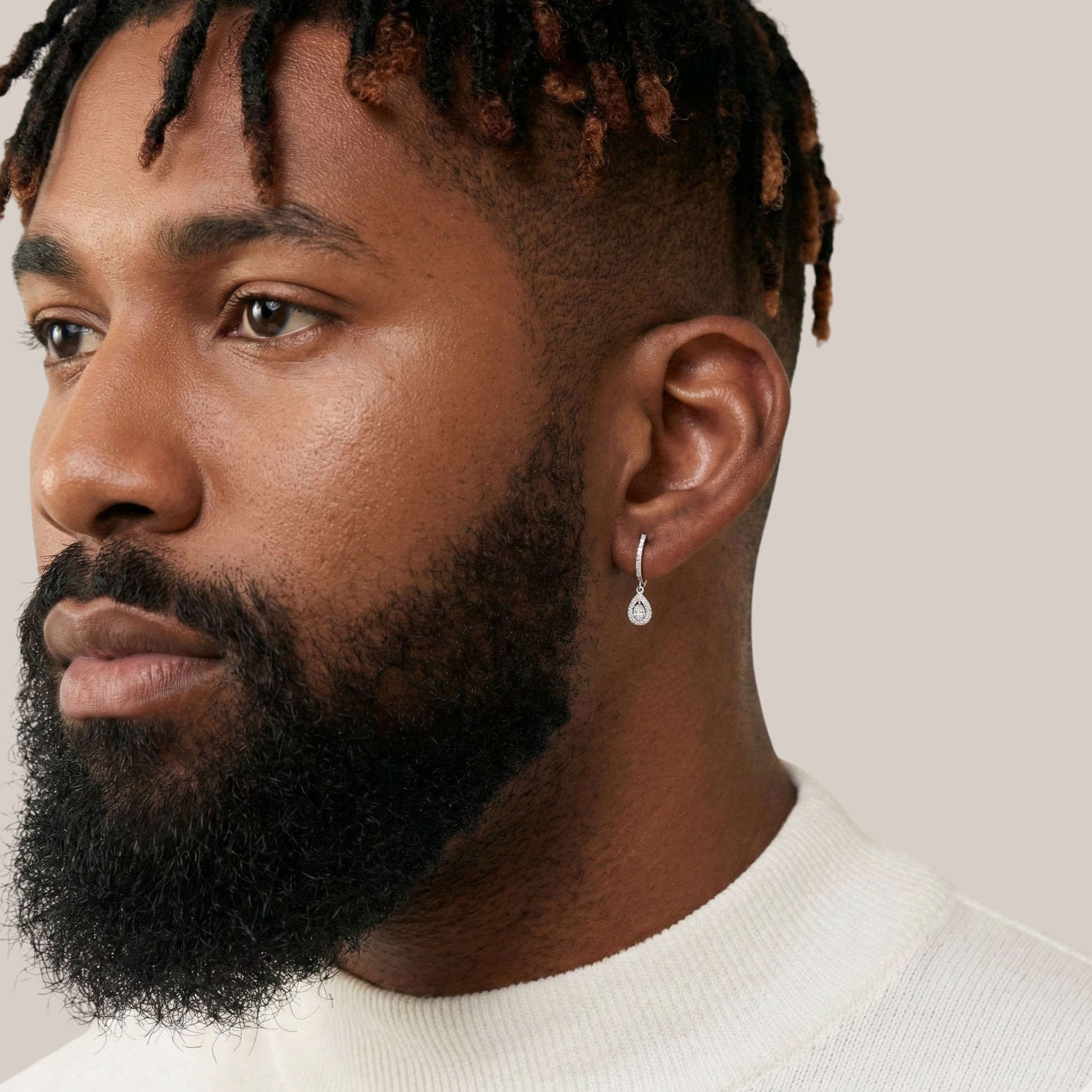 Man with a beard wearing a white sweater against a neutral background