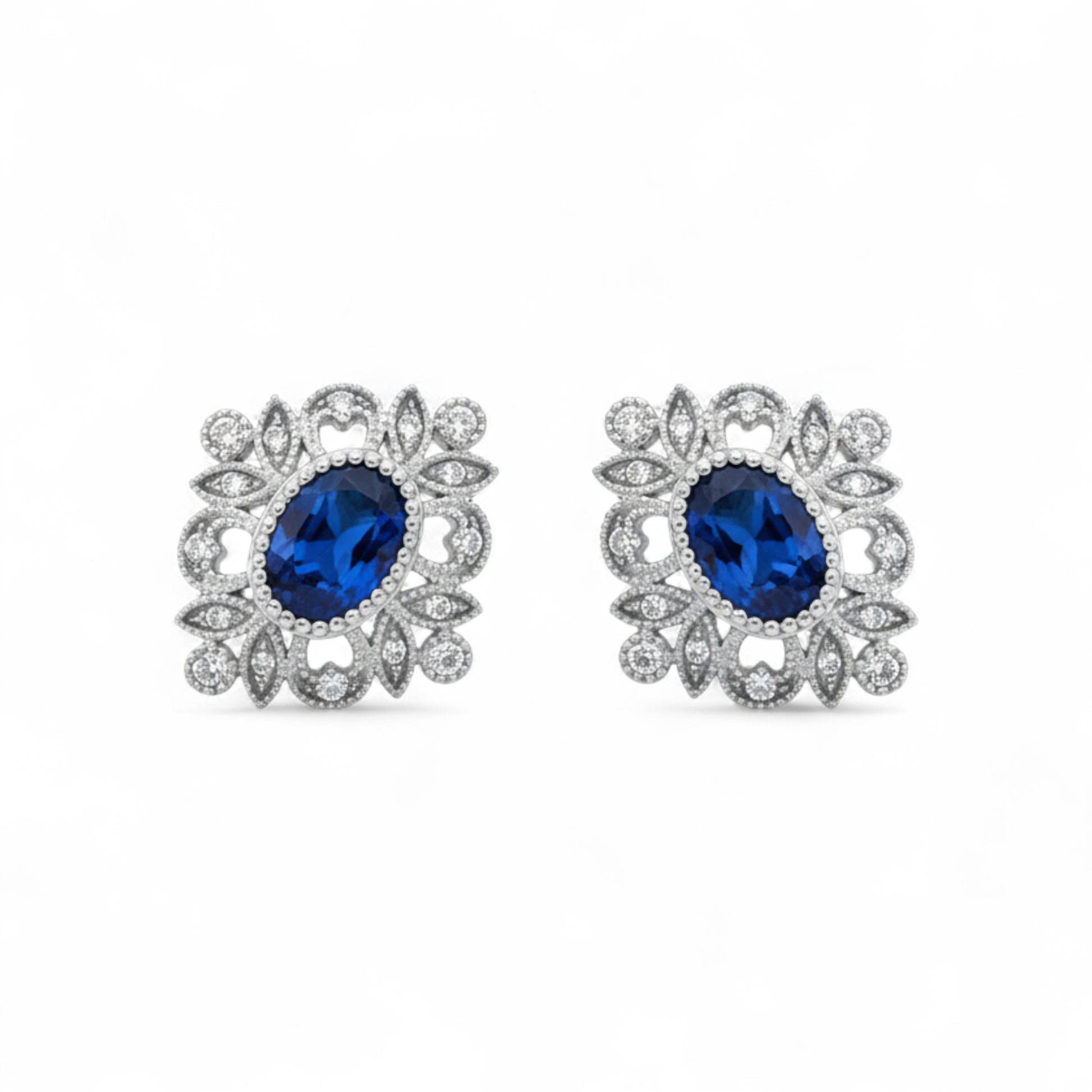 Pair of earrings with blue gemstones and silver floral designs on a white background
