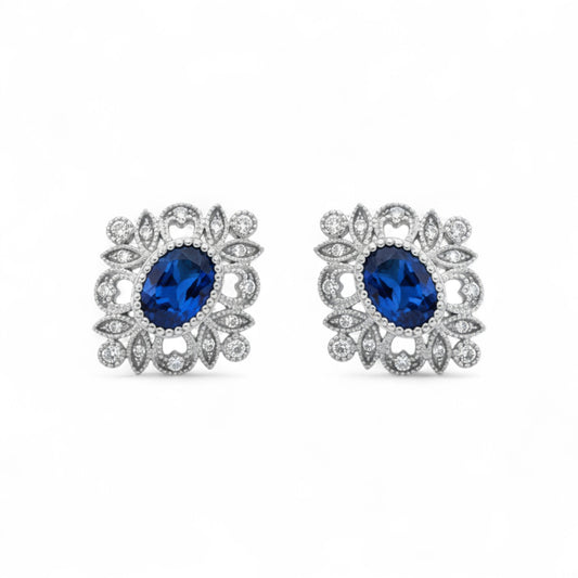 Pair of earrings with blue gemstones and silver floral designs on a white background