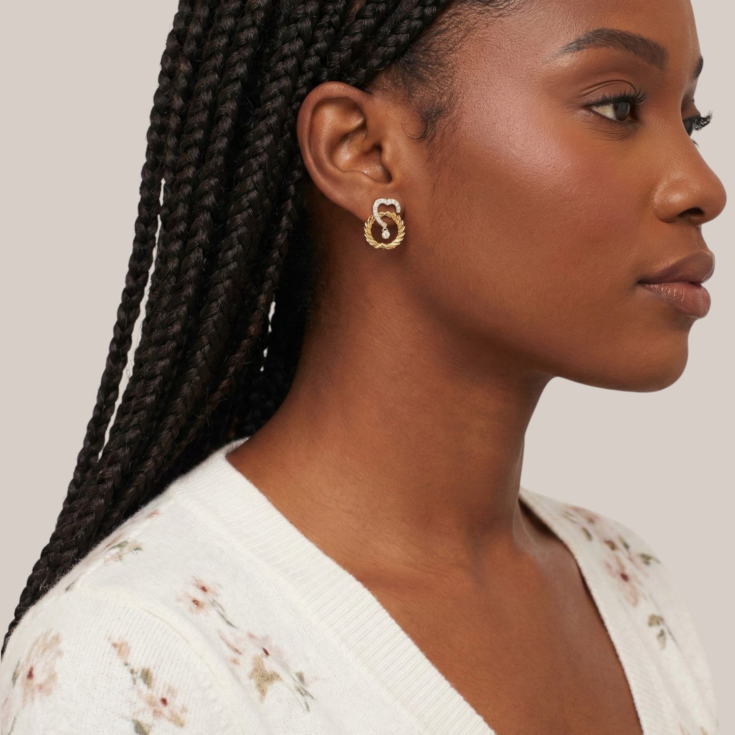 Woman with braided hair wearing gold earrings on a neutral background