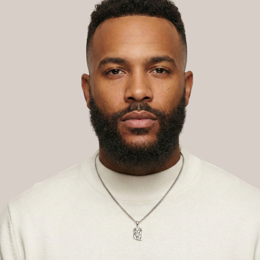 Man wearing a white sweater and necklace against a plain background