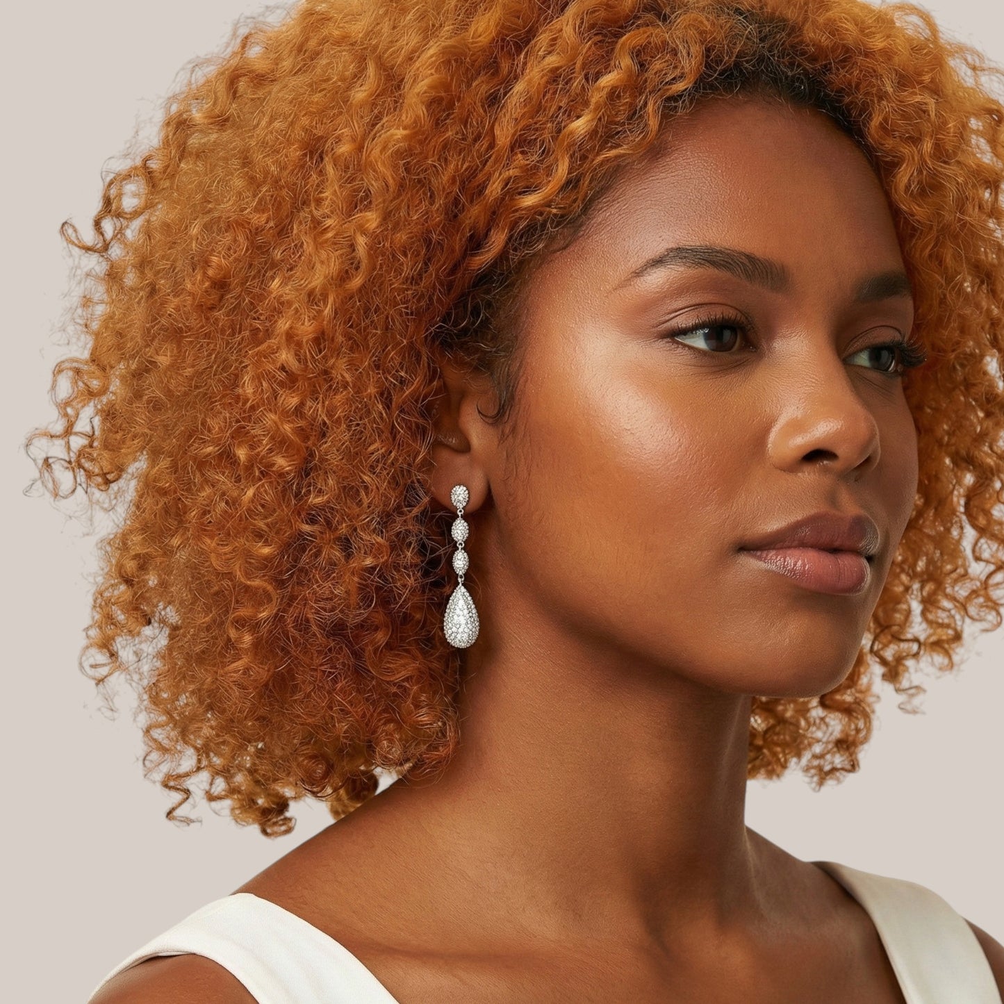 Woman with curly hair wearing a white top against a neutral background