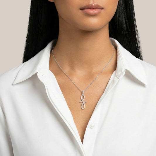Person wearing a silver necklace with a unique pendant against a neutral background