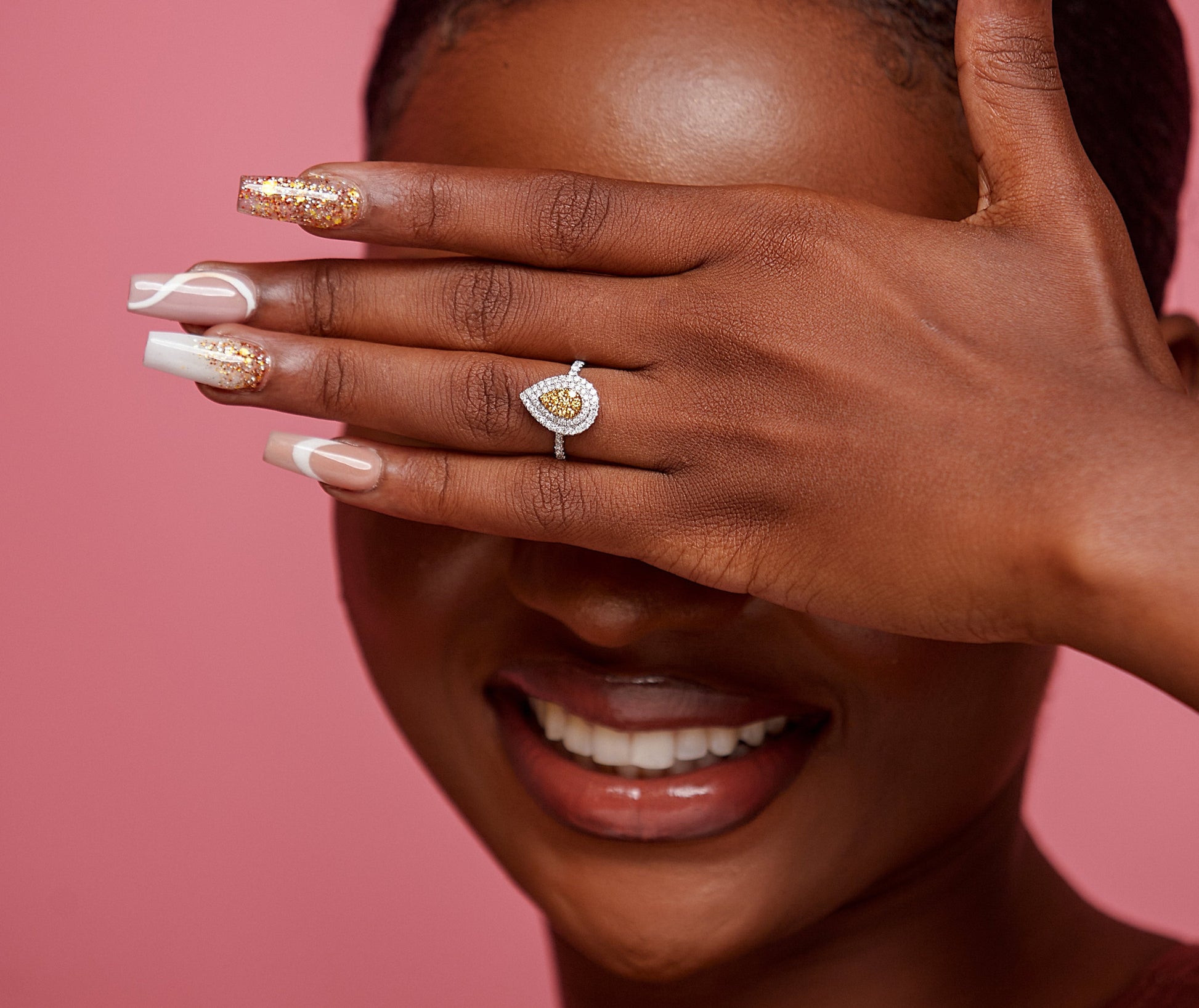 A person showcasing an 18 karat gold engagement ring with a pear cut natural diamond on their finger.