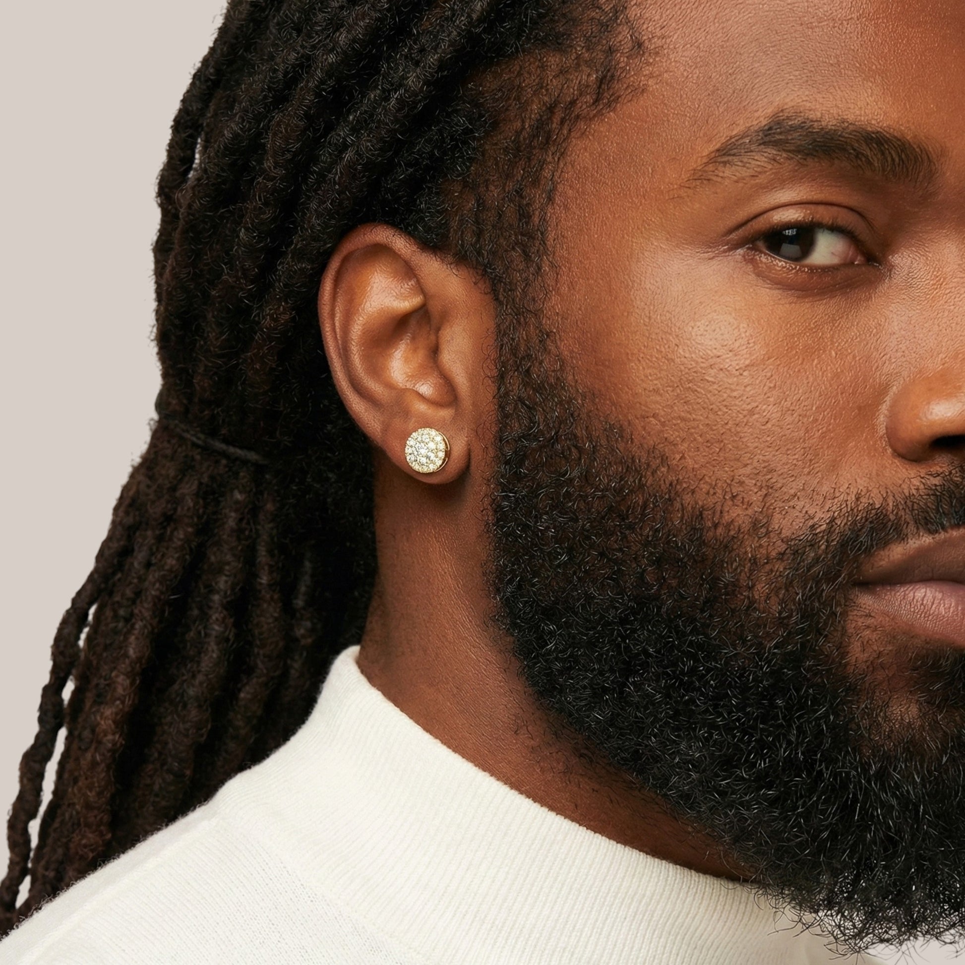 Close-up of a person wearing a diamond earring with a neutral background