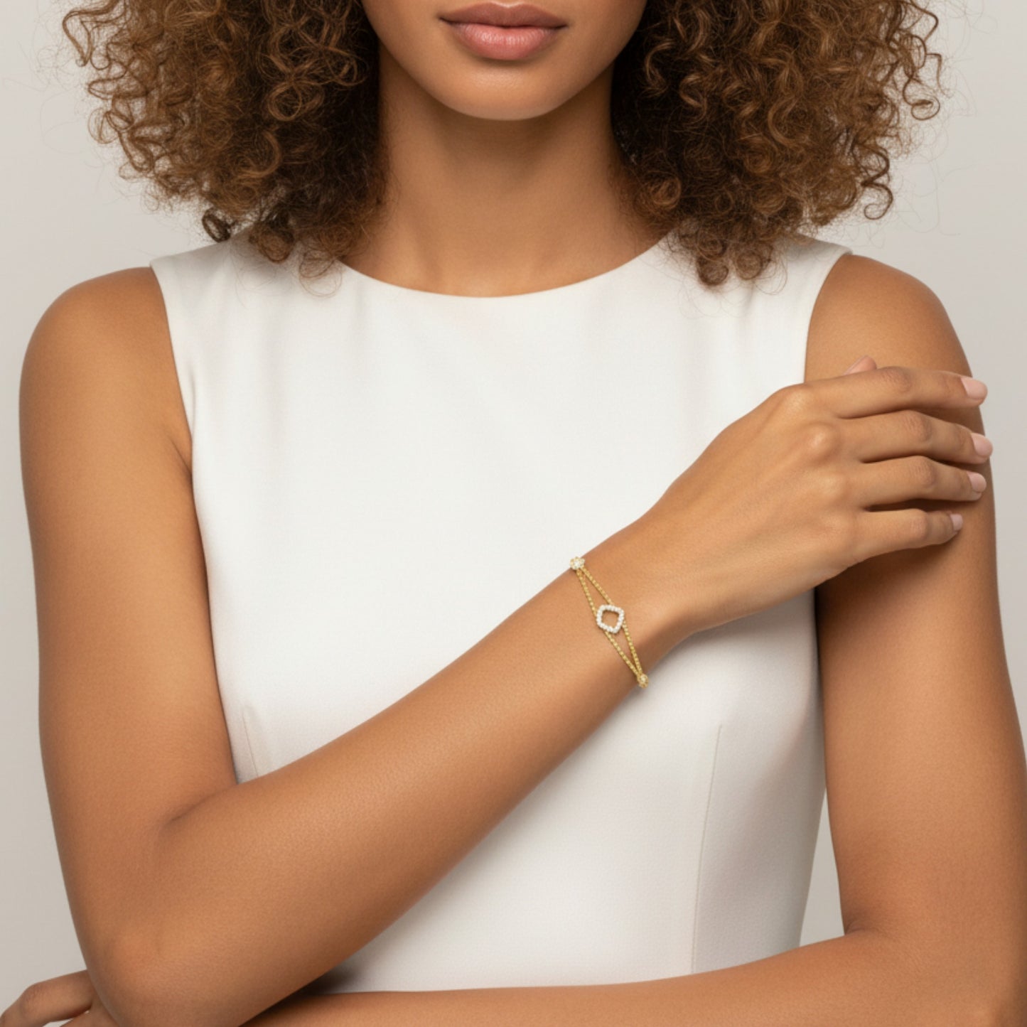 Woman wearing a gold bracelet on a plain background