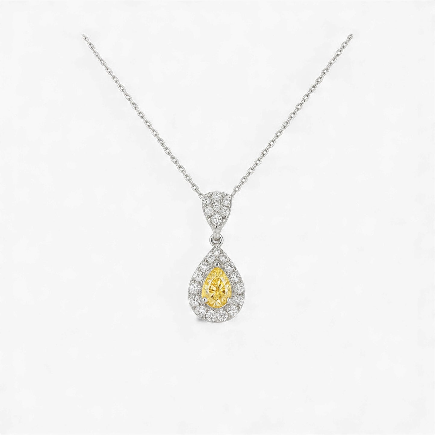 Teardrop-shaped yellow gemstone pendant with diamond accents on a white background