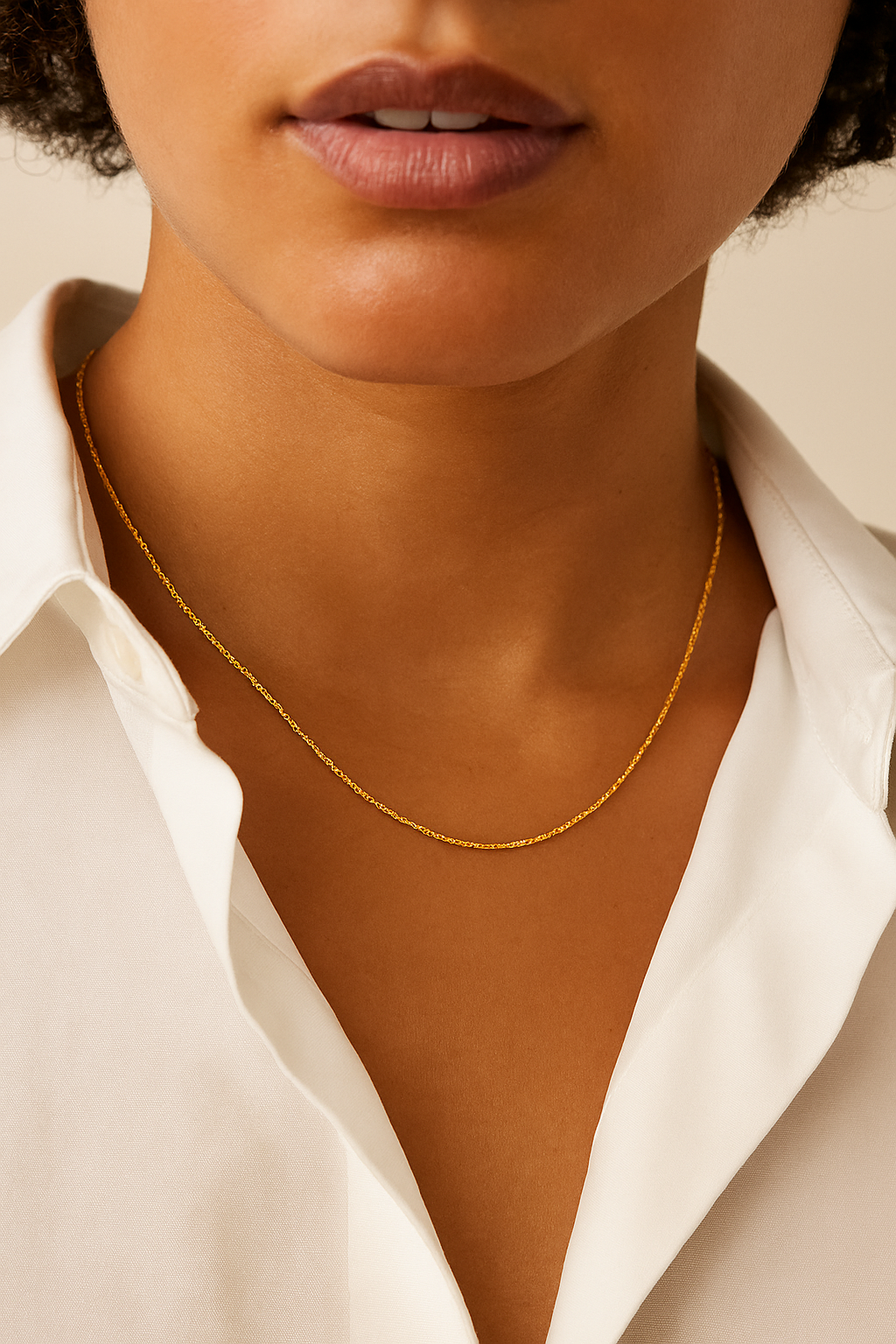 Close-up of a person wearing a gold necklace with a white shirt.