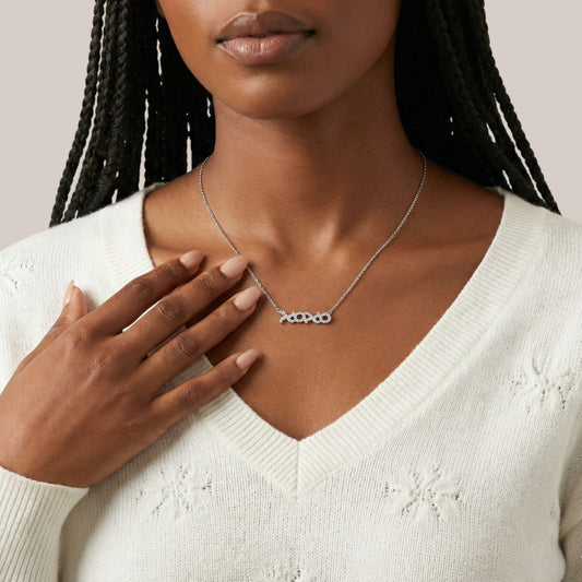 Woman wearing a silver necklace with a minimalistic design on a neutral background