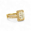 Gold ring with a large diamond and smaller diamonds on the band against a white background