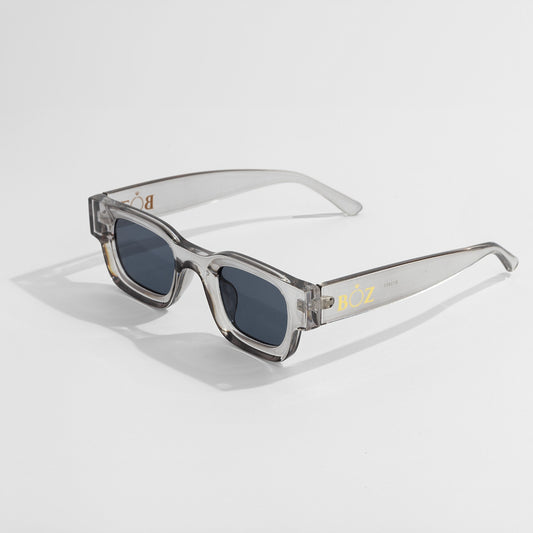 Sunglasses with clear frame and dark lenses on a light gray background