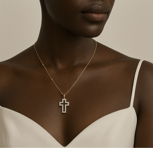 Woman wearing a gold necklace with a cross pendant against a neutral background
